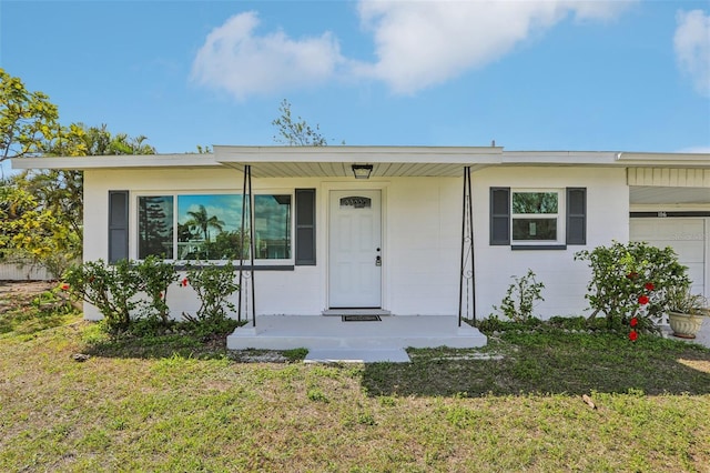 view of front of property with a garage, concrete block siding, and a front lawn