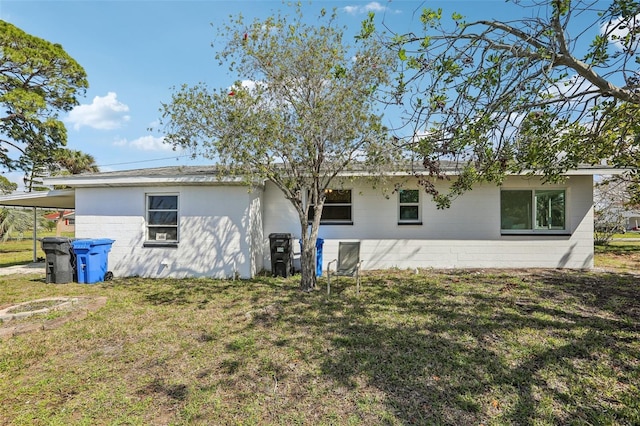 rear view of property with concrete block siding and a lawn