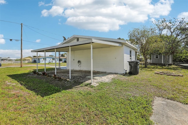 view of home's exterior featuring a carport, concrete block siding, and a lawn