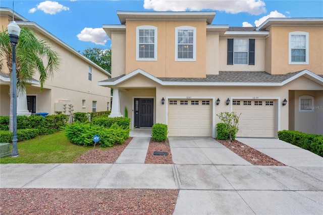 multi unit property featuring a shingled roof, concrete driveway, an attached garage, and stucco siding