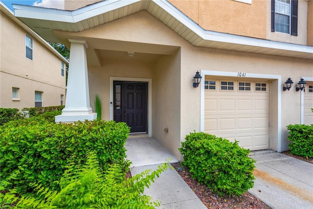 entrance to property with a garage and stucco siding