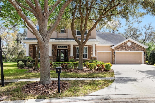 view of front of property with a shingled roof, concrete driveway, an attached garage, a front yard, and stone siding