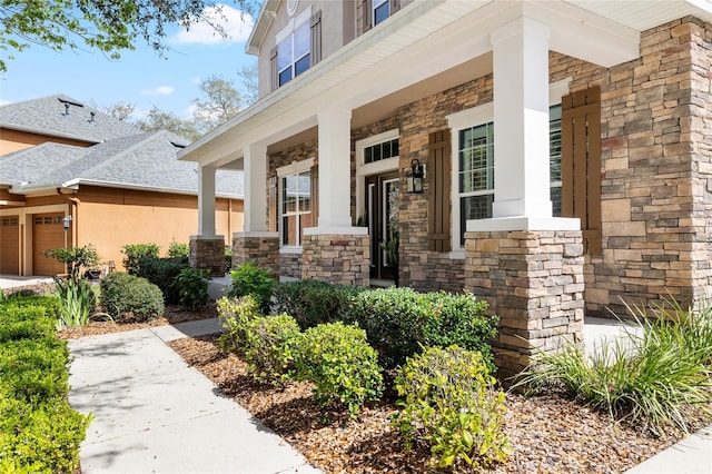 property entrance featuring a porch, stone siding, an attached garage, and stucco siding