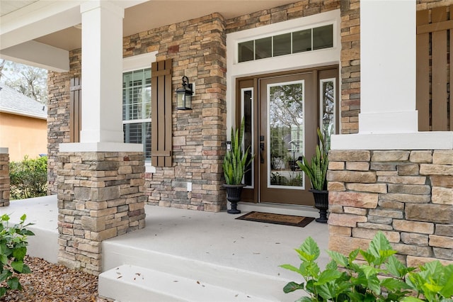 entrance to property featuring covered porch and stone siding