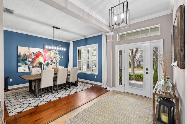 foyer entrance with crown molding, a notable chandelier, visible vents, baseboards, and hardwood / wood-style flooring