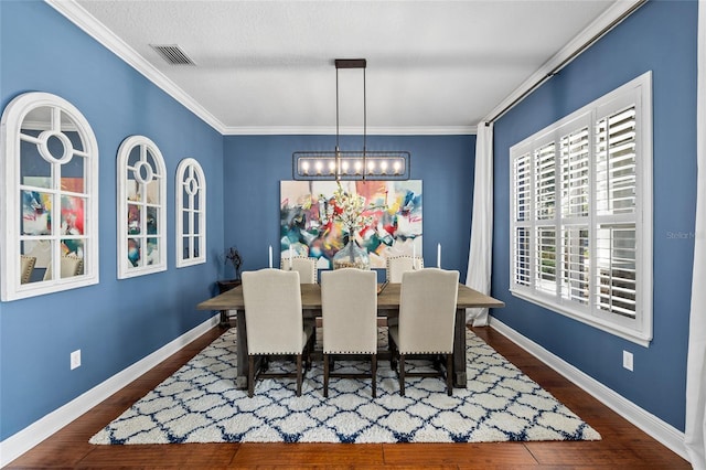 dining room with baseboards, visible vents, wood finished floors, and ornamental molding