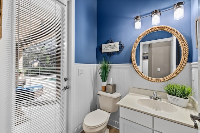 bathroom with wainscoting, vanity, and toilet