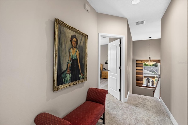 hall with baseboards, visible vents, and carpet flooring