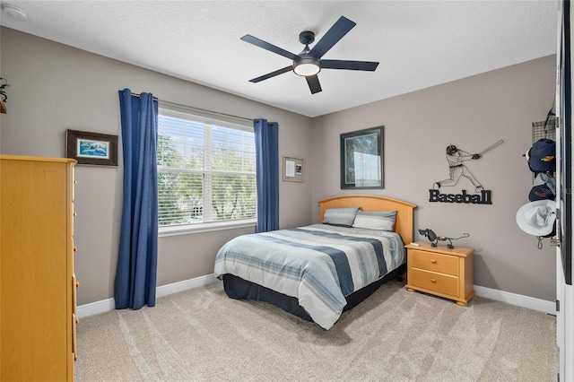 carpeted bedroom with ceiling fan, a textured ceiling, and baseboards