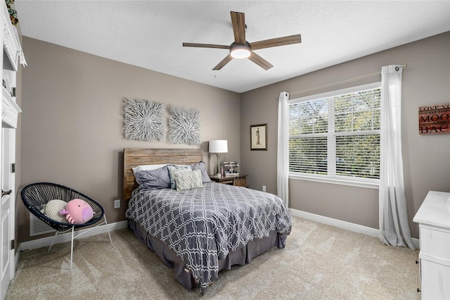 carpeted bedroom featuring a textured ceiling, ceiling fan, and baseboards