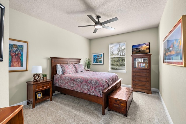 bedroom with a ceiling fan, light colored carpet, a textured ceiling, and baseboards