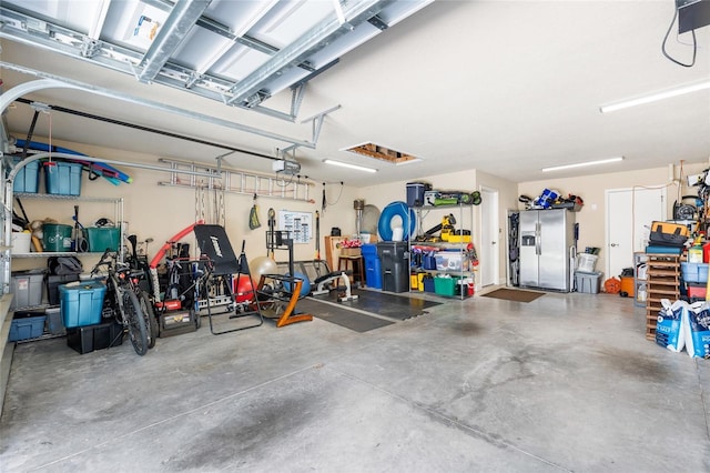 garage with a garage door opener and stainless steel fridge with ice dispenser