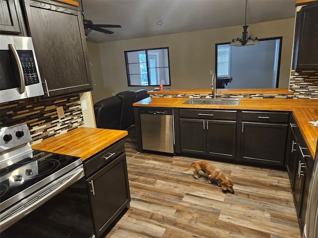 kitchen with light wood-style floors, wood counters, appliances with stainless steel finishes, and a sink