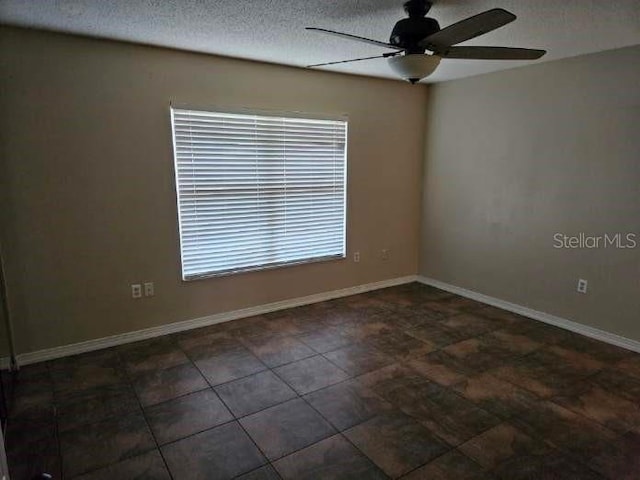 empty room with a textured ceiling, ceiling fan, and baseboards