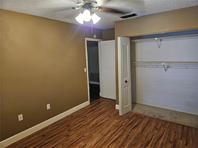 unfurnished bedroom with a textured ceiling, a closet, wood finished floors, and visible vents