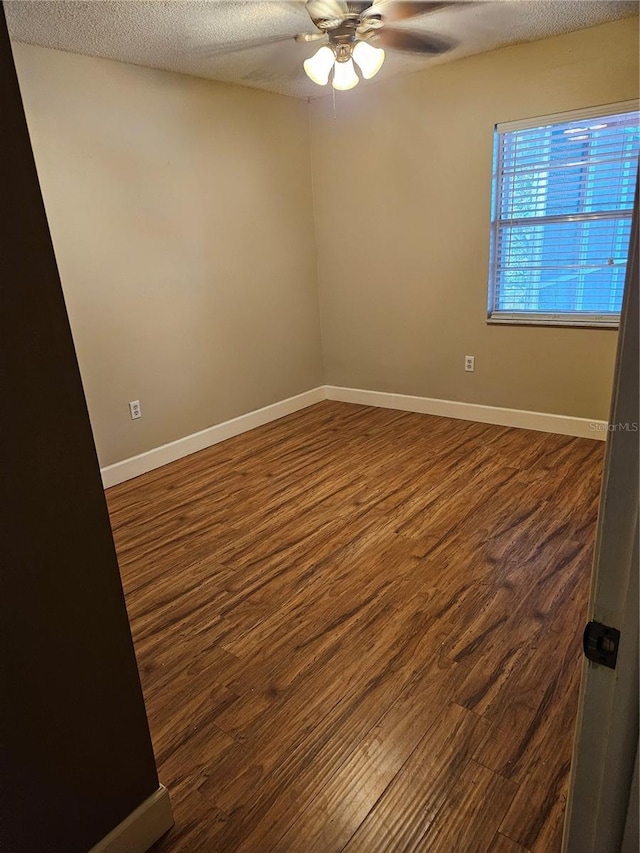 spare room with ceiling fan, a textured ceiling, baseboards, and wood finished floors