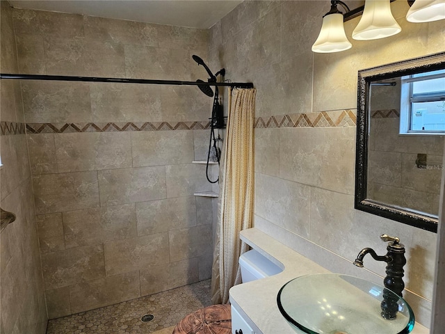 full bath with a tile shower, tile walls, and vanity