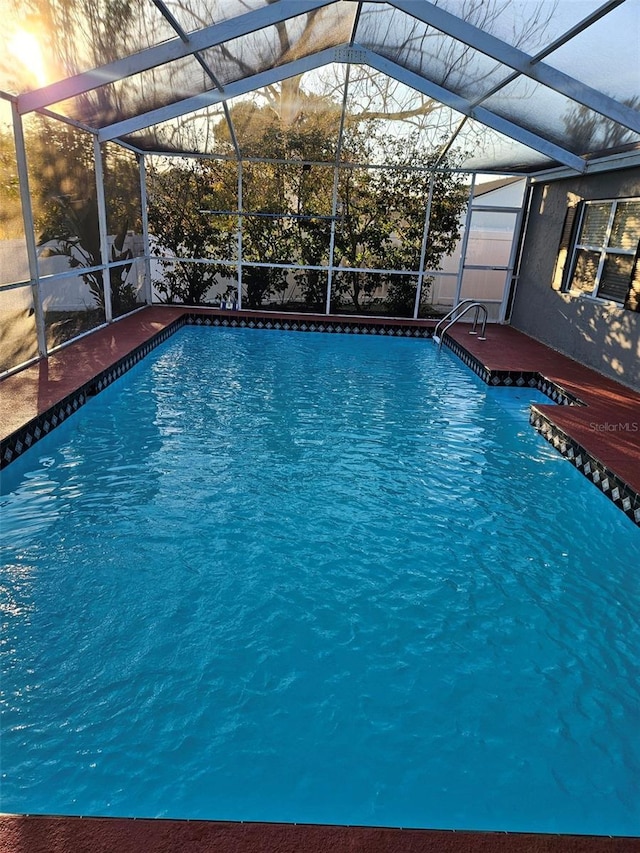 outdoor pool featuring glass enclosure and a patio