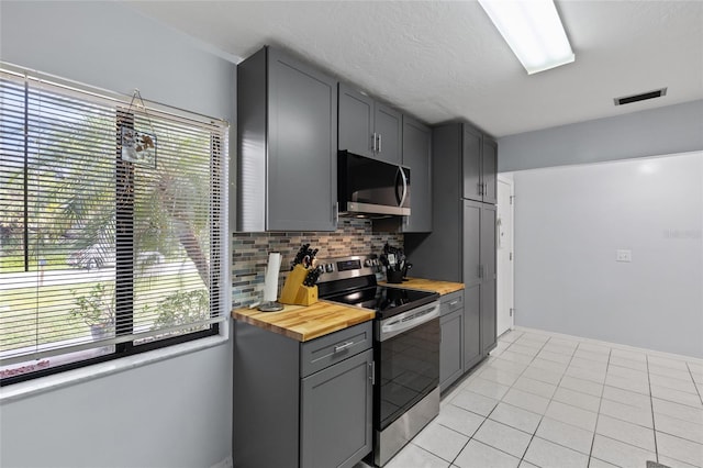 kitchen with stainless steel range with electric stovetop, butcher block counters, visible vents, and gray cabinets