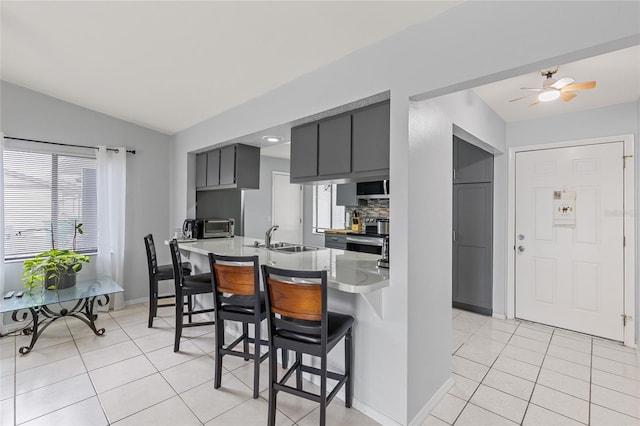 kitchen with light countertops, a sink, a kitchen breakfast bar, and light tile patterned floors