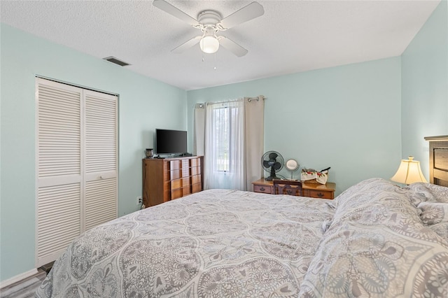 bedroom featuring a textured ceiling, ceiling fan, a closet, and visible vents