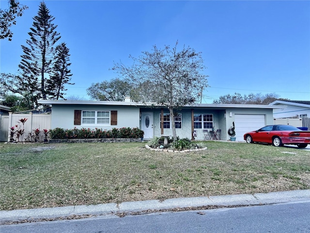 single story home with a front lawn, an attached garage, fence, and stucco siding