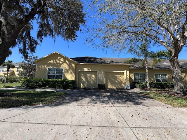 ranch-style home with driveway, an attached garage, and stucco siding