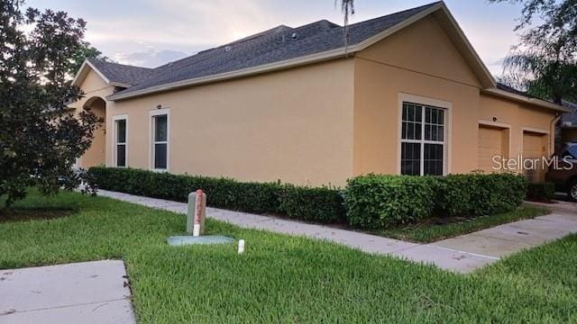 view of property exterior with a lawn, an attached garage, and stucco siding