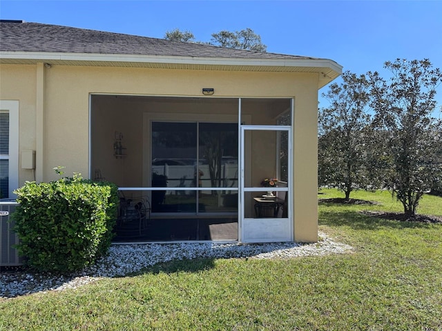 property entrance with a shingled roof, cooling unit, a yard, and stucco siding