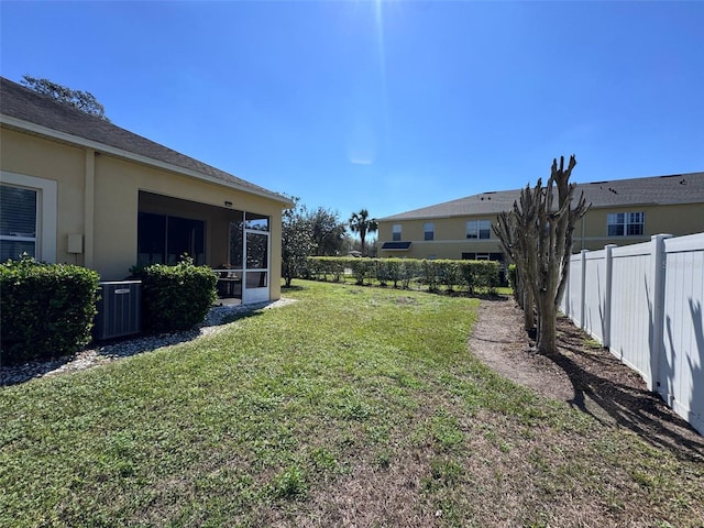 view of yard with a sunroom, fence, and cooling unit