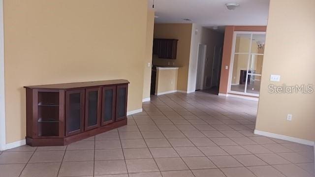 empty room with light tile patterned floors and baseboards