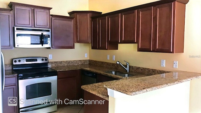 kitchen with dark brown cabinetry, appliances with stainless steel finishes, light stone counters, a peninsula, and a sink