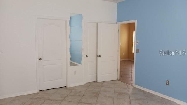 unfurnished bedroom with a closet and baseboards