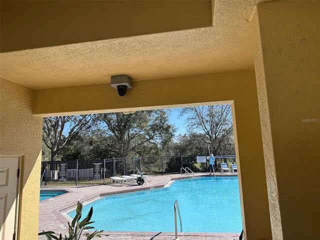 community pool with a patio and fence