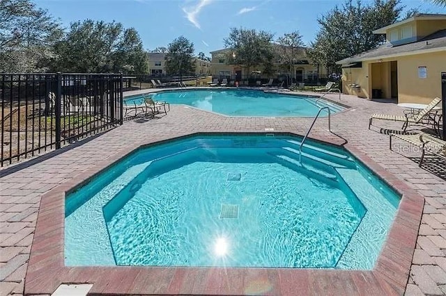 pool featuring a community hot tub, fence, and a patio