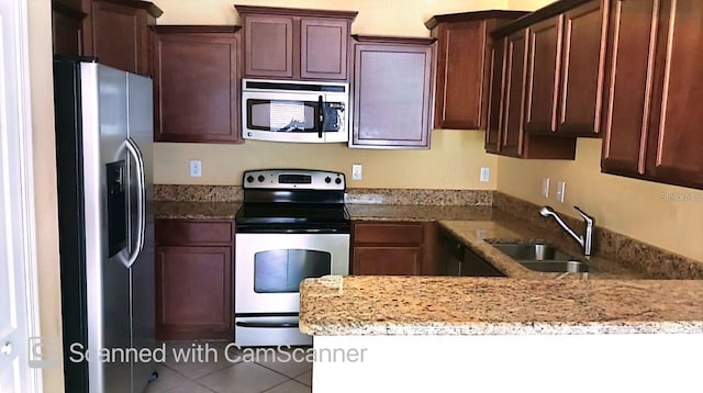 kitchen with appliances with stainless steel finishes, tile patterned flooring, a sink, and light stone counters