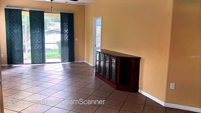 tiled spare room featuring baseboards and a ceiling fan