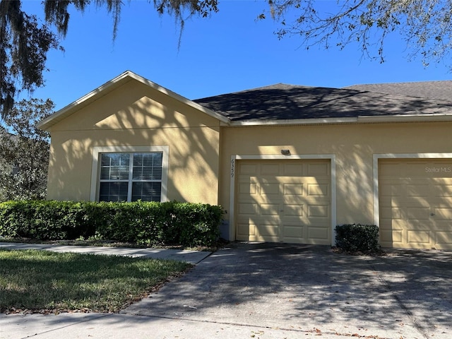 view of home's exterior featuring a shingled roof, driveway, an attached garage, and stucco siding