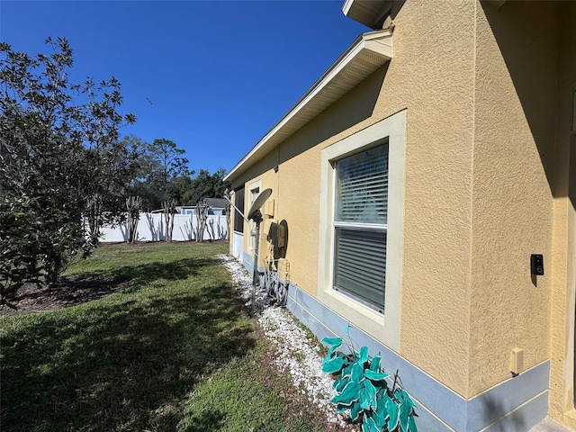 view of home's exterior with a yard, fence, and stucco siding