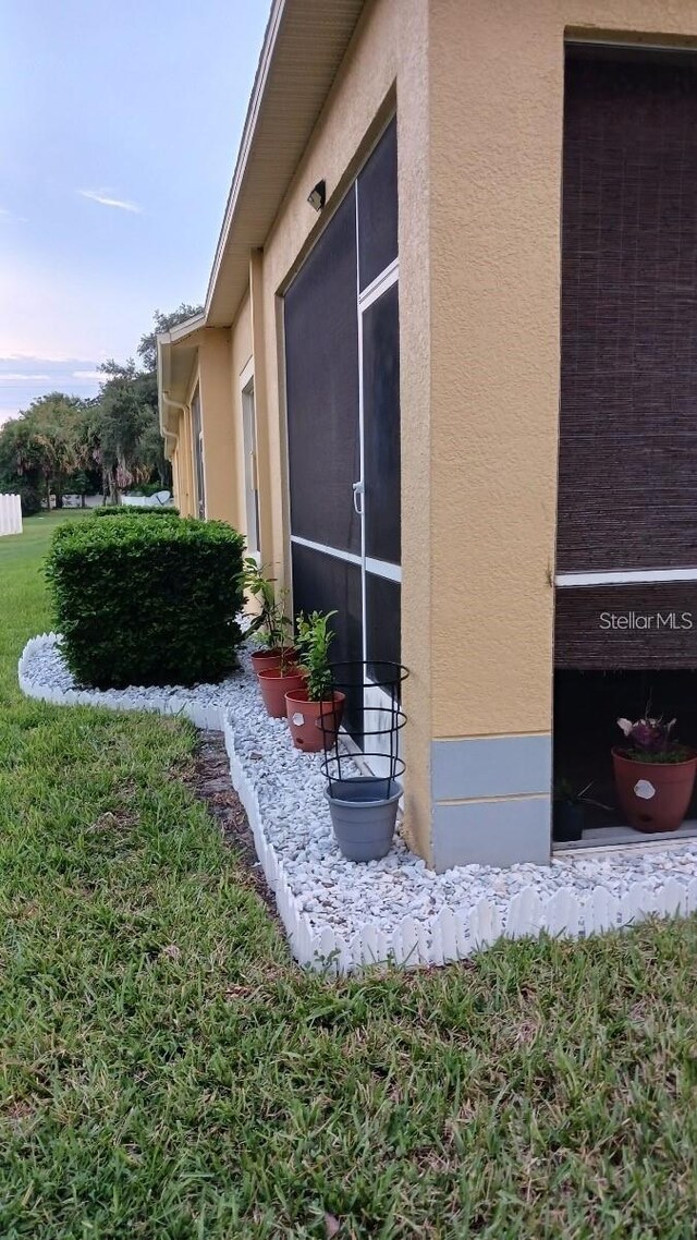 view of side of home with a lawn and stucco siding