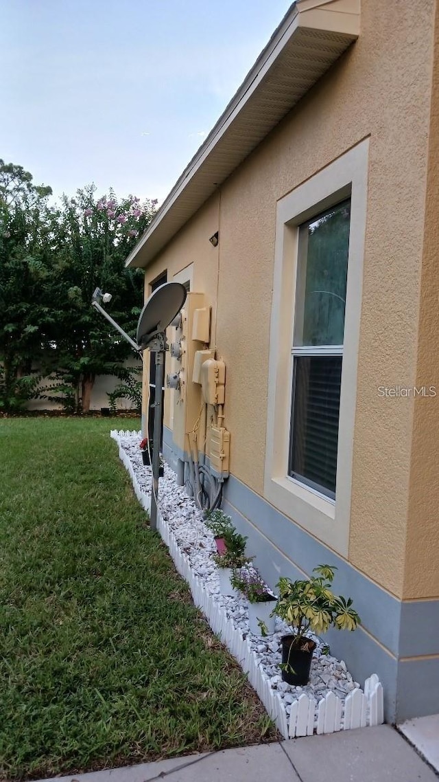 view of side of home featuring a yard and stucco siding