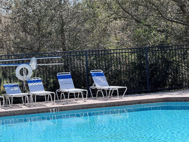 community pool with a patio area and fence