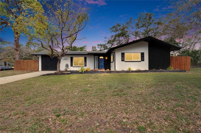 view of front of home featuring a yard, concrete driveway, and fence