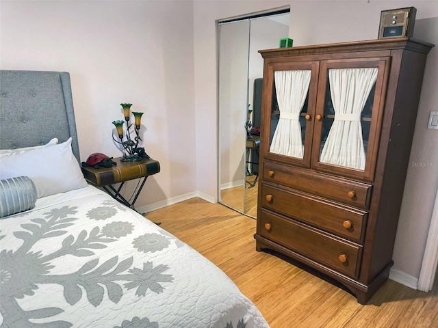 bedroom featuring light wood finished floors, a closet, and baseboards