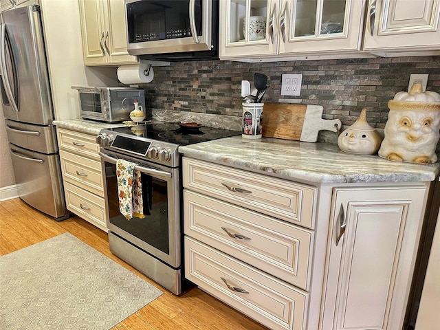 kitchen featuring appliances with stainless steel finishes, cream cabinetry, and light wood-style floors