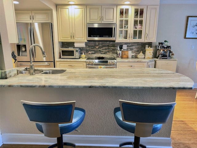 kitchen featuring a toaster, decorative backsplash, a breakfast bar, stainless steel appliances, and a sink