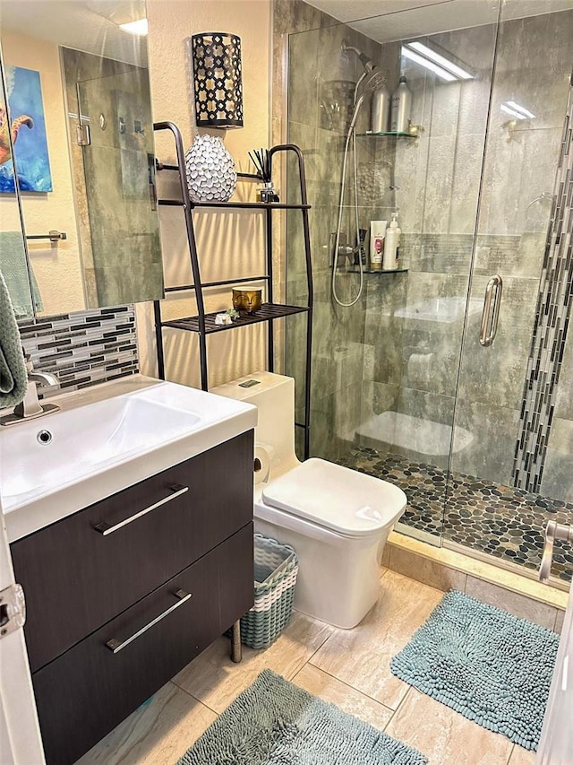 bathroom with tasteful backsplash, a stall shower, vanity, and toilet