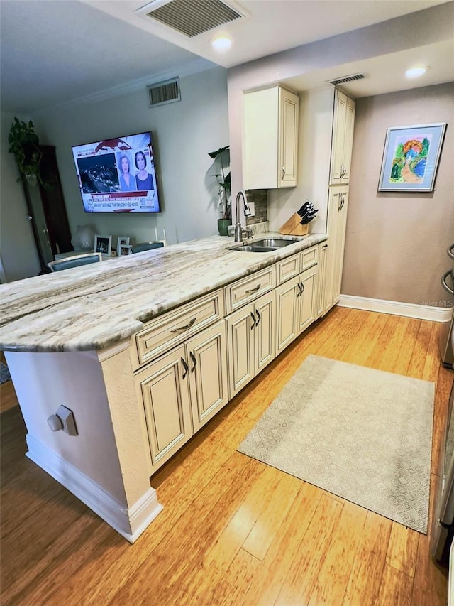 kitchen featuring visible vents, a peninsula, cream cabinets, and light wood finished floors