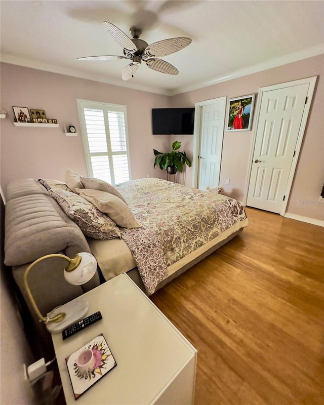 bedroom with a ceiling fan, crown molding, baseboards, and wood finished floors