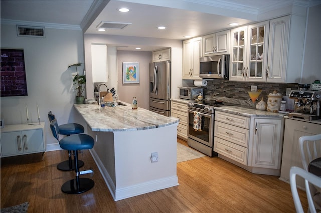 kitchen featuring visible vents, appliances with stainless steel finishes, a kitchen breakfast bar, and a sink